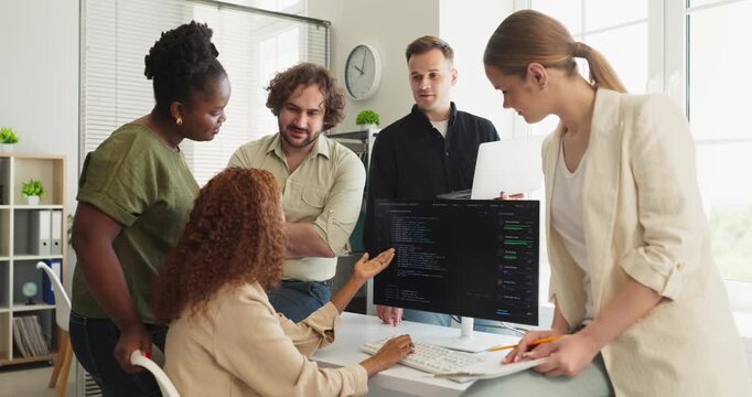 Developers code review meeting discussion in office. Programmers discuss source code at computer screen, plan tasks, and improve quality under lead guidance. Clear concept of team collaboration.