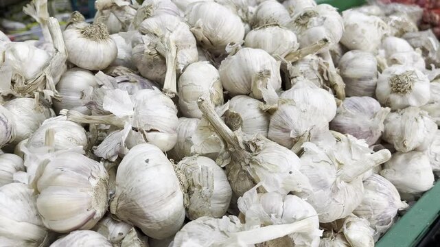 A large pile of fresh raw garlic bulbs displayed at a traditional local market