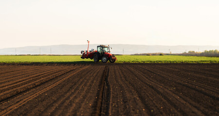 Fototapeta premium Modern tractor planting corn with precision seeder on agricultural field
