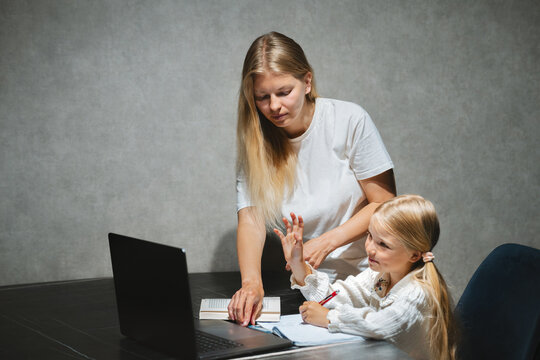 Mom helping her daughter with homeschooling education studying in online school with laptop at home, child on distance learning family lifestyle modern technology and parent tutor support