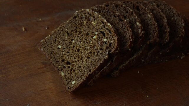 Hand takes slice of cereal sourdough rye bread close up. Detailed texture of healthy wholegrain bread rich of fiber, healthy eating concept.