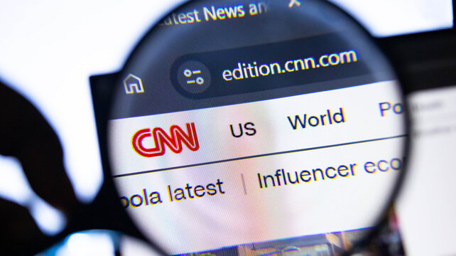 Close-up of CNN website on screen. Magnifying glass zooming in online news. Journalism and media concept.