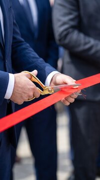 Official cutting a red ribbon with scissors. Grand opening ceremony event. Business launch milestone.