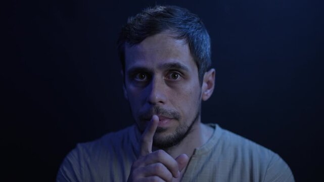 Man gestures "shh" by putting finger to lips