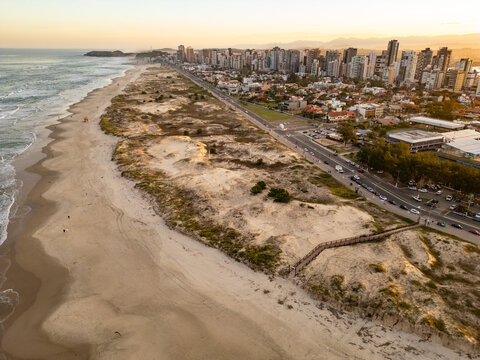 Drone View of Torres Beach with Dunes, Vegetation and City Buildings at Sunset, Brazil