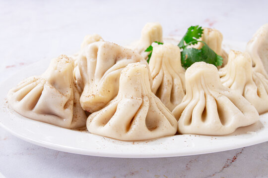khinkali, on a white oval plate, decorated with greenery, on a light background, Georgian cuisine, no people,