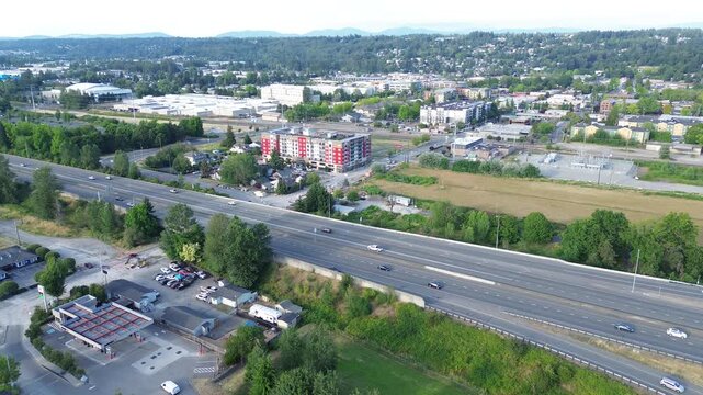 Transit corridor overview state route 167 bridges across logistical plots near downtown Kent. Angular buildings cast sharp shadows upon paved surfaces, highlighting freight infrastructure in WA