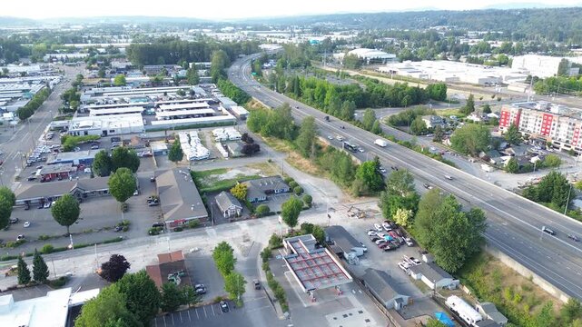 Warehouse distribution hub interstate 167 runs parallel to storage facilities defining Kent landscape. Geometric rooftops deep green trees fill frame under clear skies, forming arteries in WA