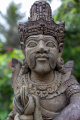 Obraz premium Closeup of head and hat of stone carved statue of a god on wall of Hindu temple in Bali