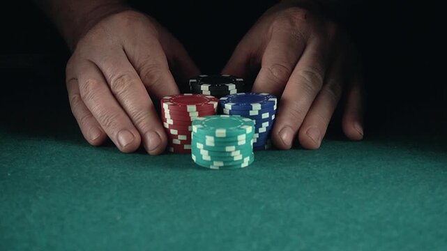 Hands arranging colorful poker chips on a green felt table, showcasing a gradual buildup of a stack in a gaming environment