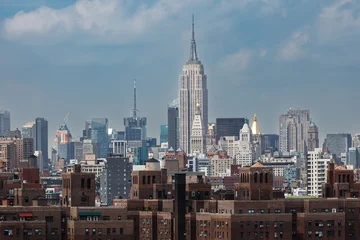 Famous skyline of New York City with Empire State building featured in the center behind historic brownstone buildings © Pete Niesen Photo