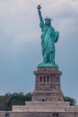 The Statue of Liberty stands tall on Liberty Island, with tourists visiting the base of the statue. © Pete Niesen Photo