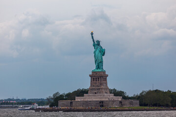 The Statue of Liberty stands tall on Liberty Island, with tourists visiting the base of the statue. © Pete Niesen Photo