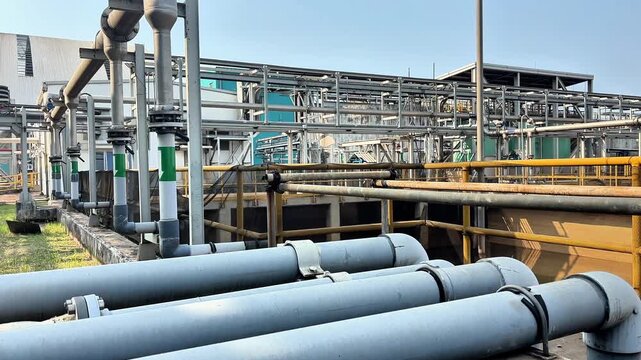 Large gray drain pipes run across industrial site