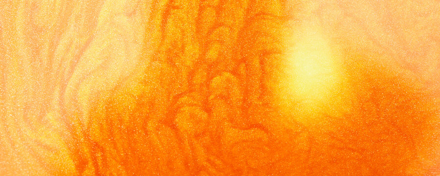 Shimmering gold abstract background. Liquid gold texture waves and swirls. Beautiful shiny yellow texture with glitter. Liquid gold metallic paint close-up.