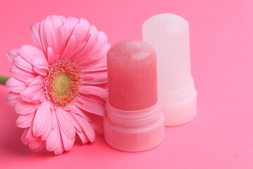 Obraz premium Natural crystal alum deodorant with a pink flower on a pink background