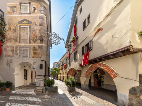 Cuneo, Italy - Picturesque narrow alley Contrada Mondovi in the historic center of Cuneo,  featuring ancient brick arches, traditional porticoes, cobblestone pavement, and  frescoed palace walls 