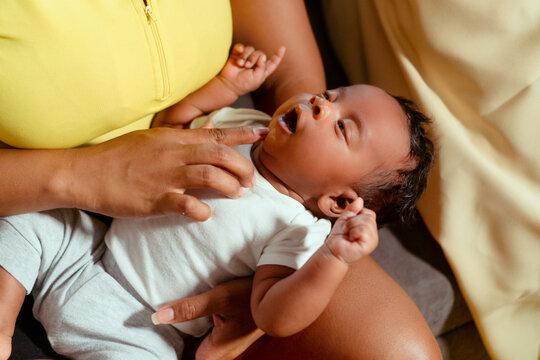 Mother gently caring for her yawning newborn infant