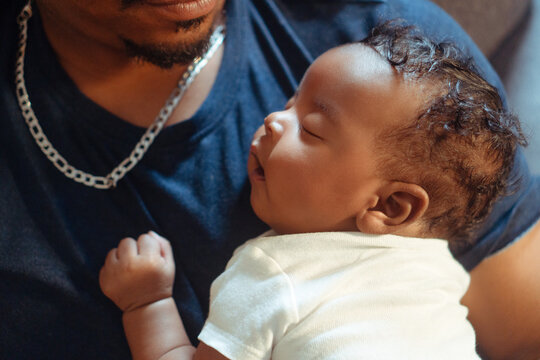 Father gently holding sleeping newborn baby