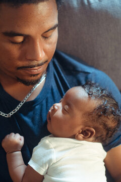 Father cradling sleeping infant in loving embrace