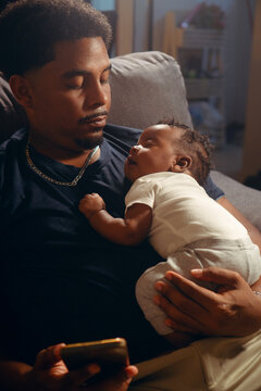 Father holding sleeping dark skinned baby, nurturing family bond