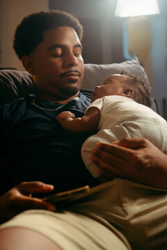 Father holding newborn baby sleeping peacefully at home