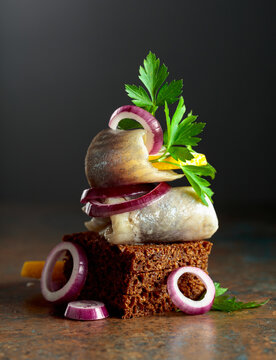 Rye bread canape with herring filet, red onion, lemon, and parsley.