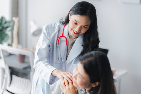 Asian Young Doctor Comforting Older Patient in Clinic Office Hea