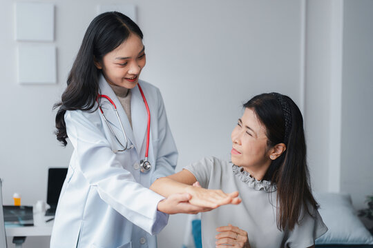 Asian Young Doctor Examines Older Asian Woman's Arm Mobility in