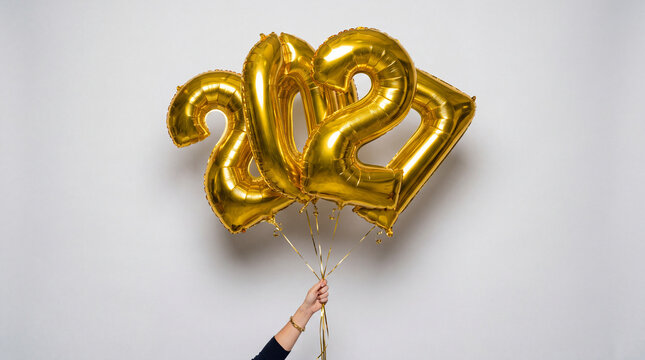 Hand holding golden 2027 foil balloons against clean white background