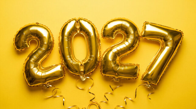 Golden foil balloons forming 2027 on bright yellow background with curling ribbons