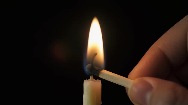Candle being lit by a match in darkness with cinematic motion and shallow depth of field