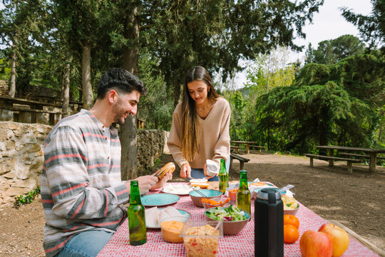 Couple enjoying outdoor picnic lunch at forest table