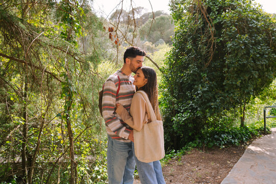 Romantic couple hugging on a sunny forest trail in spring