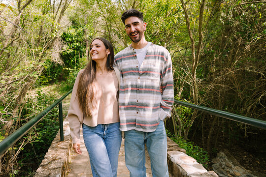 Smiling couple walking on a forest bridge in spring