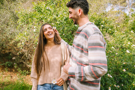 Young couple laughing in garden as he tucks a flower