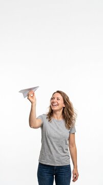 Joyful woman launching a paper airplane against a white background symbolizing dreams and aspirations