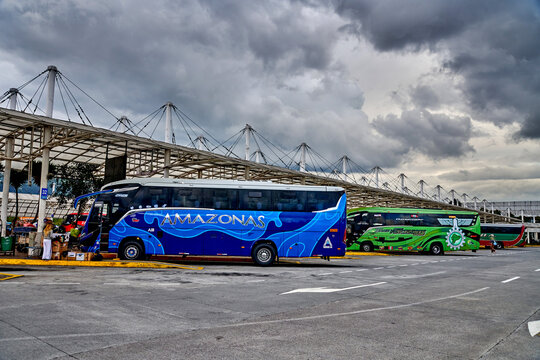 Quito, Ecuador - May 12, 2026: Blue Amazonas bus parked at terminal Bus Station Quito Sur (Terrestre Quitumbe) with green bus and cloudy sky in background, modern transportation infrastructure