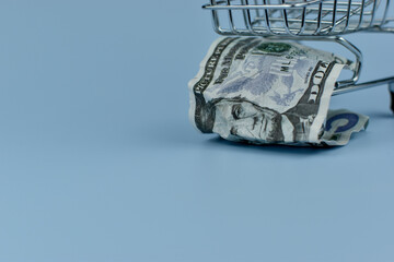 Mini shopping cart holds crumpled bills © Nazir