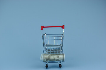 Mini shopping cart beside crumpled dollar bill © Nazir