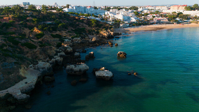 serene and picturesque rocky coastline at sunset with beachfront buildings and turquoise water, aerial view from above the town on the beachside, Praia dos Aveiros Portugal