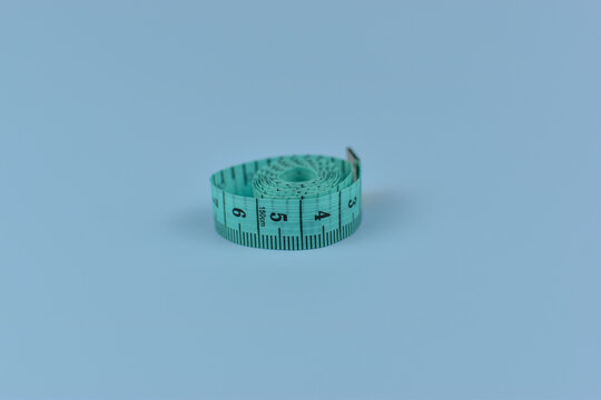 Coiled teal tape measure rests on pale blue background