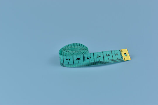 Coiled teal tape measure rests on pale blue background