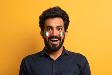 Fototapeta premium Smiling Indian Male With Face Paint In National Colors, Expressing Joy And Excitement In Studio Setting, Celebrating A Sports Event. Energetic Young Adult Man Showing Passion And Enthusiasm.