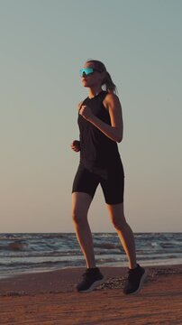 Woman running on beach at sunset in sportswear. Healthy lifestyle and fitness