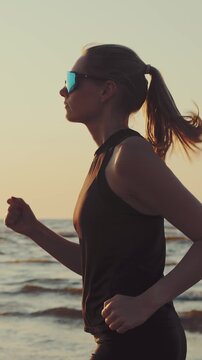 Woman running on beach at sunset in sportswear. Healthy lifestyle and fitness