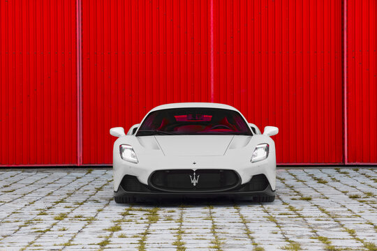 A white Maserati MC20 against a red tin wall. Front view. Engine 3.0l V6 Twin Turbo, 630 HP, 730 Nm, Max speed 325 km-h, RWD. Katowice, Poland, 23.09.2021