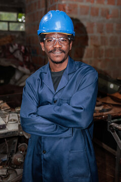 Smiling African worker stands in workshop with tools after successful working day