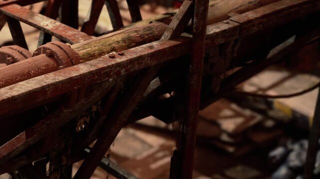 Rusty machinery sits idle in a dimly lit workshop. The tools around show signs of age and wear. Dust fills the air as light filters through small gaps above.