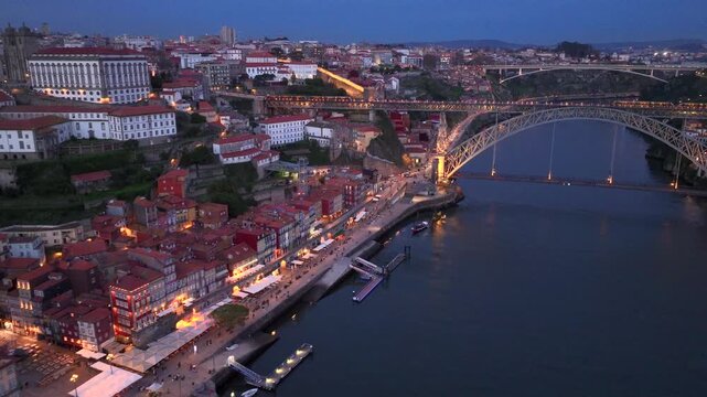 Illuminated Evening Porto City with Dom Luis I Bridge over Douro river. Aerial Shot over Night Lights and Infrastructure
